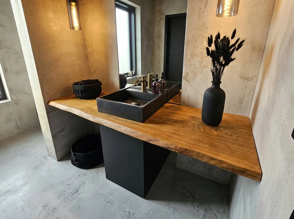 Salle de bain design industriel avec vasque à poser rectangulaire noire en pierre/béton, robinetterie dorée laiton brossé, sur plan de travail en chêne massif live-edge