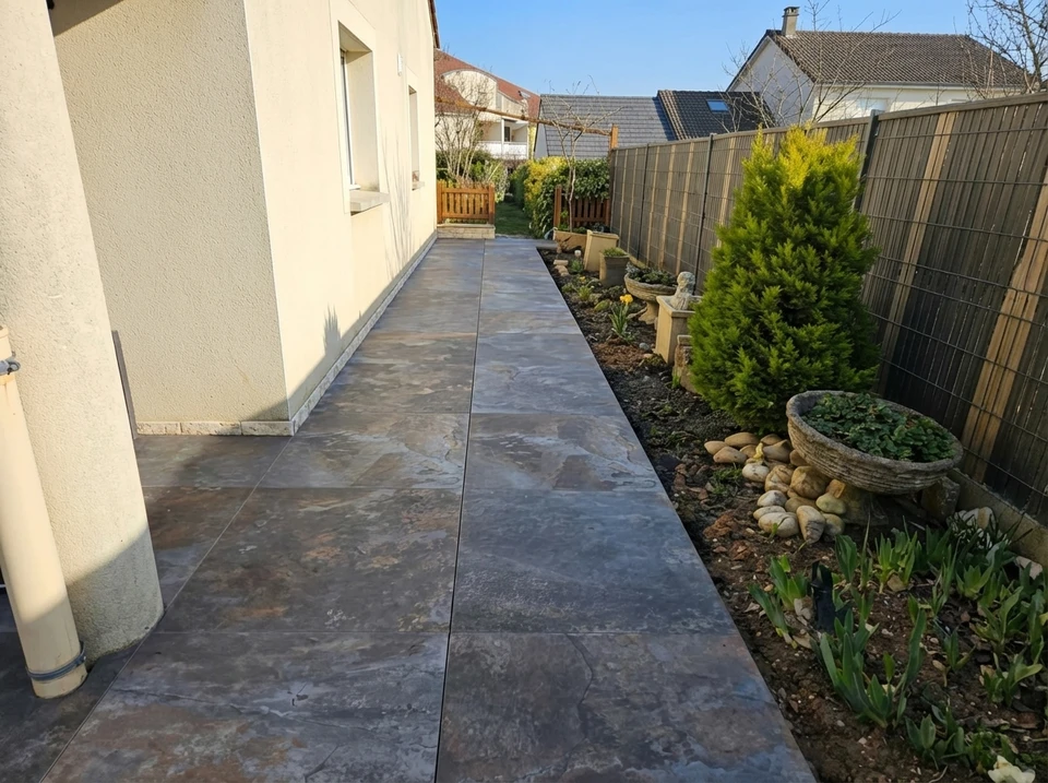 Terrasse extérieure moderne avec mobilier de jardin noir en résine tressée sur dallage pierre naturelle
