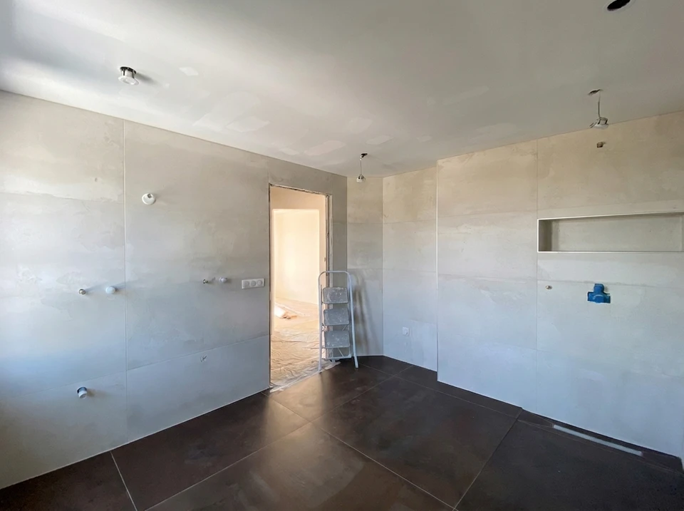 Photographie réaliste d'une salle de bains moderne rénovée avec carrelage mural élégant, vasque design, et finitions de qualité. La scène montre une salle de bains complète et aménagée professionnellement, illustrant le résultat final d'un projet clé en main coordonné par un seul artisan. L'image doit capturer la qualité du travail et l'aménagement intérieur complet.