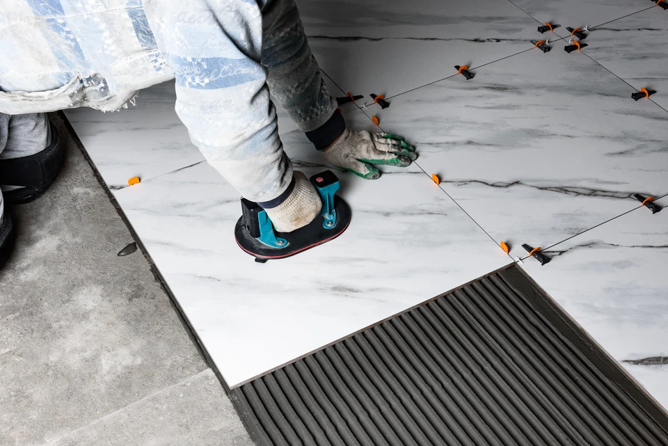 Ouvrier carreleur installant des carreaux de c&eacute;ramique bleus sur mur int&eacute;rieur